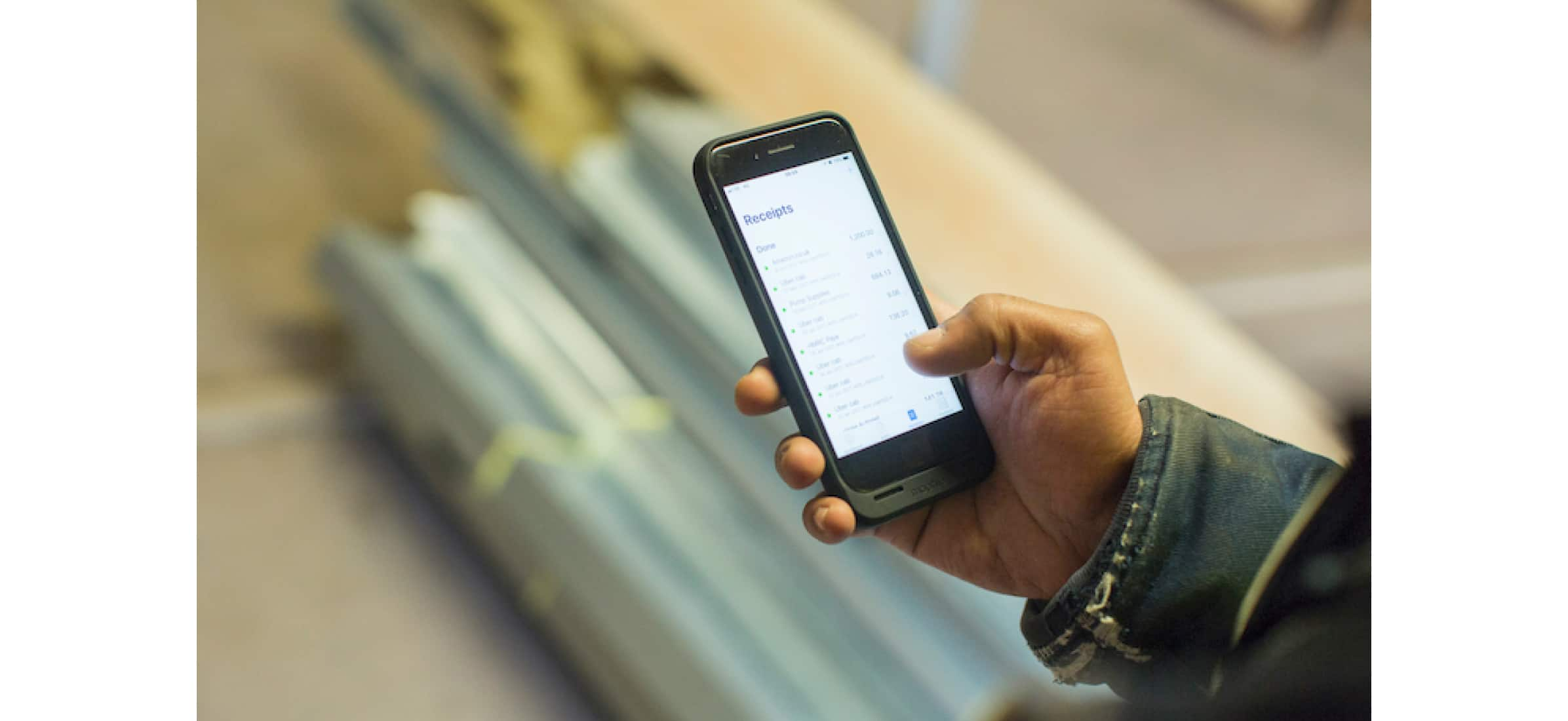 Hitesh’s hand checking his receipts on his mobile phone.